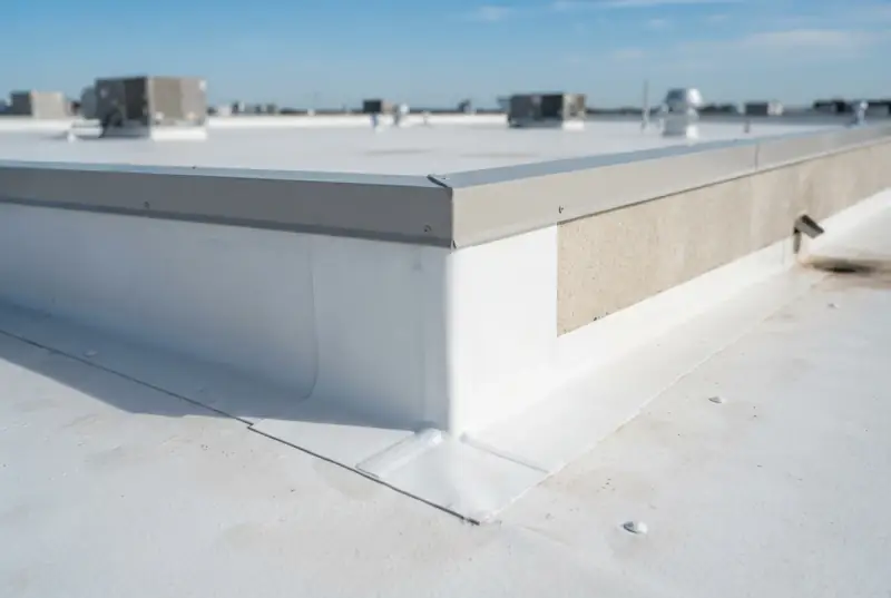 Close-up of a single-ply membrane wrapped and welded around an outside parapet corner beneath metal coping on a commercial roof